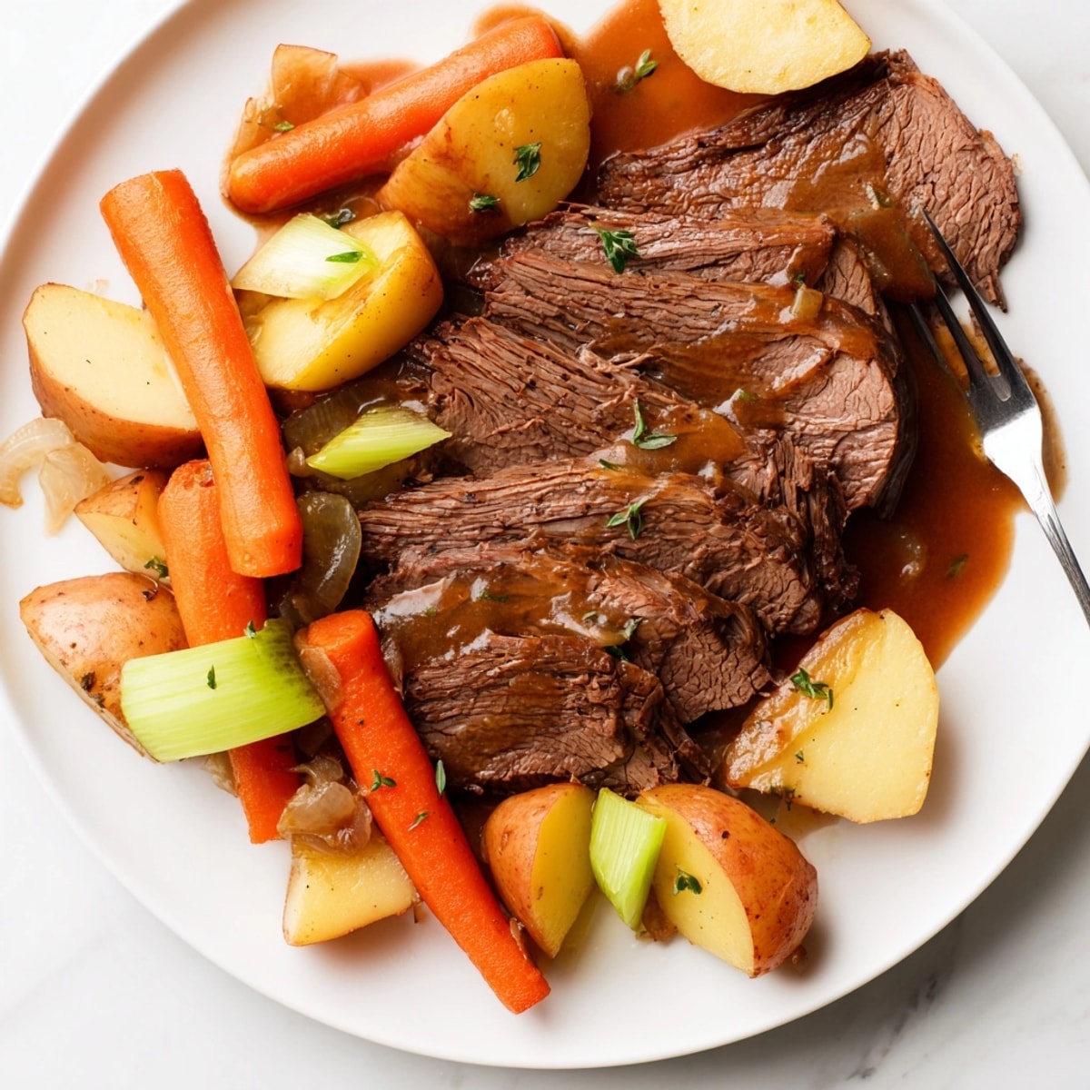 Juicy, shredded Pot Roast recipe with flavorful gravy, ready to be served over mashed potatoes.